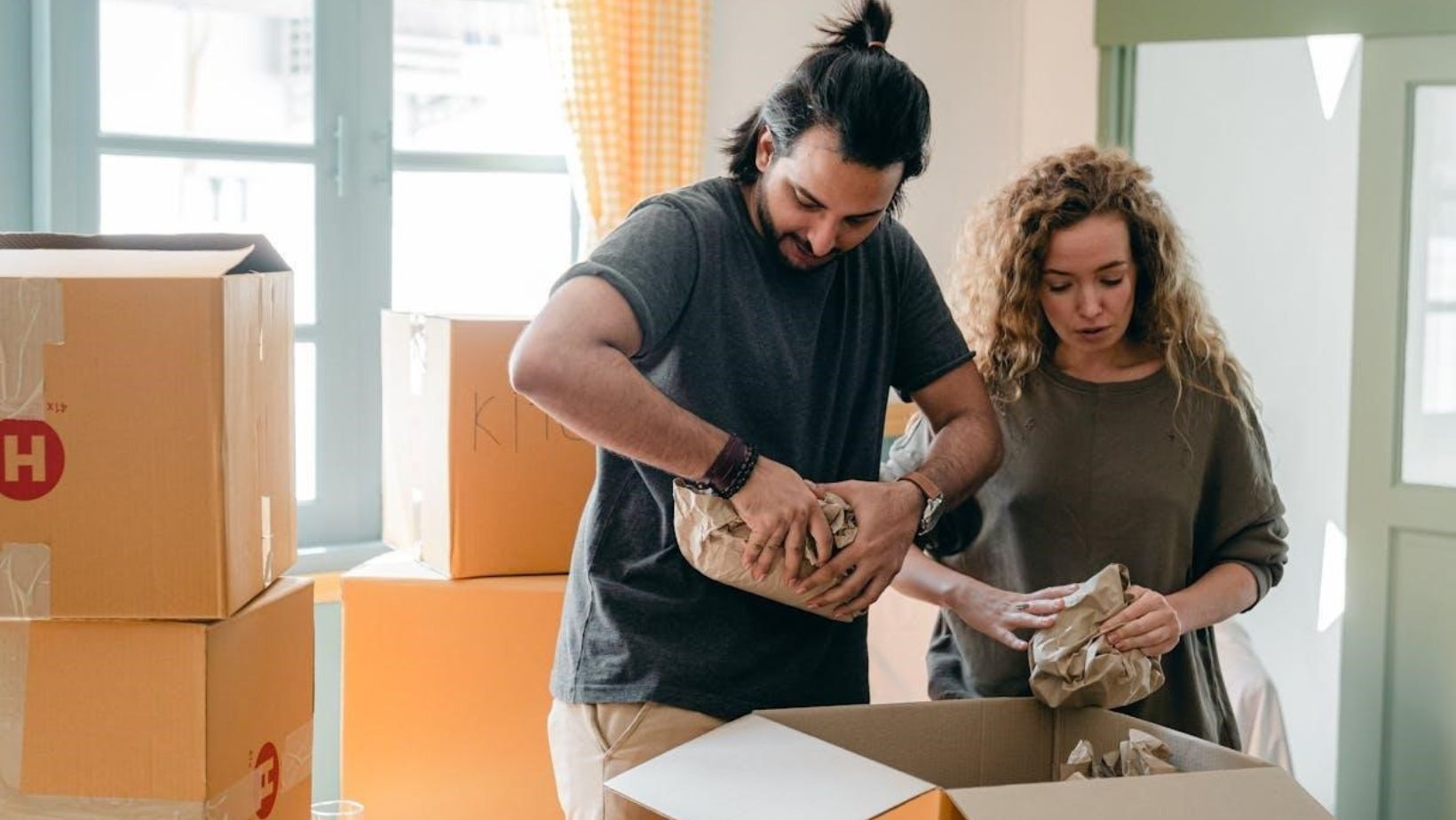 Couple packing their belongings in cardboard boxes.